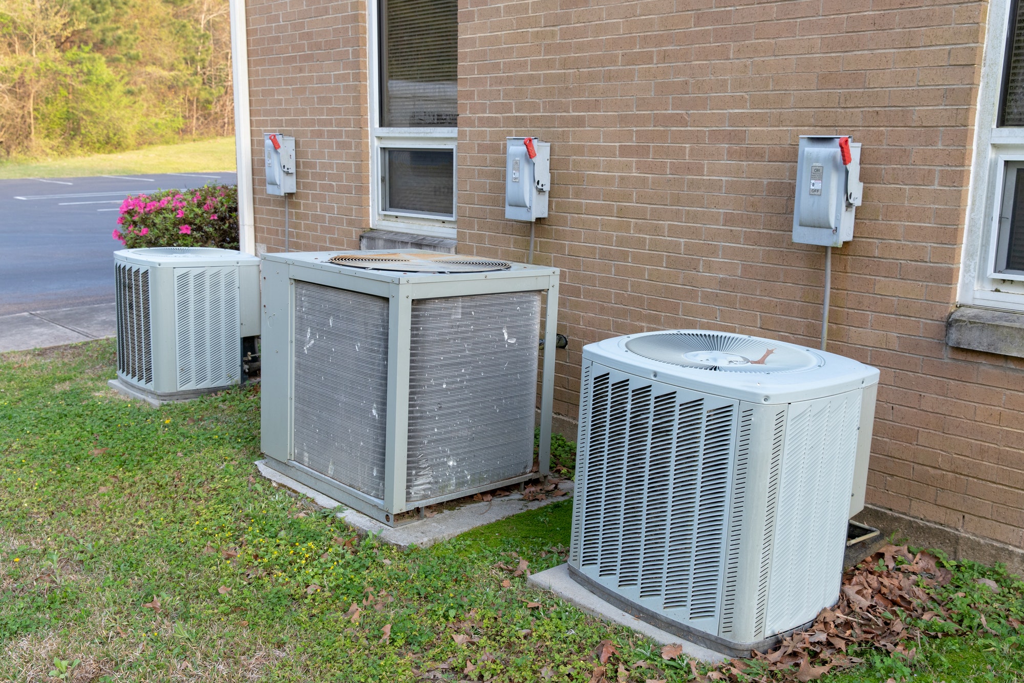 Multiple air conditioner units next to commercial building.